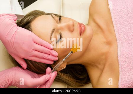 Jeune femme pendant la procédure de peeling du visage dans le salon de beauté. Peeling chimique du visage Banque D'Images