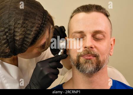 Dermatologue examine la tache de naissance du patient avec dermatoscope. Taupe check. Dermoscopie Banque D'Images