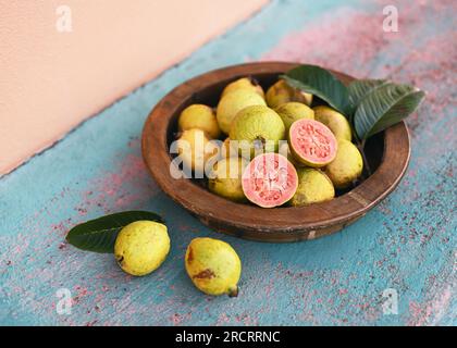 Fruits frais de goyave rose bio sur le palais en bois dans le jardin. (Psidium guajava) alimentation végétalienne saine ou concept de régime alimentaire. Mise au point sélective. Banque D'Images