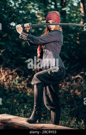 Portrait en plein air de jeune femme en costume de pirate avec une épée. Banque D'Images