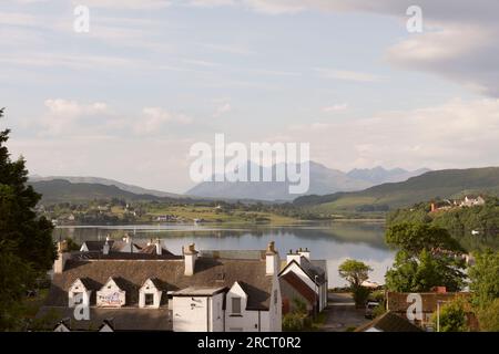 Le Cuillin du Nord Munros vu dans la distance de Portree, reflété dans le Loch Portree sur un matin calme et ensoleillé en été Banque D'Images