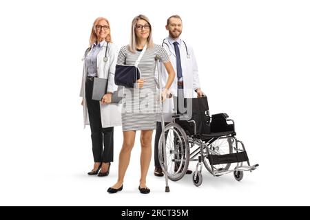 Médecins debout derrière une patiente avec une fronde de bras et une béquille isolée sur fond blanc Banque D'Images