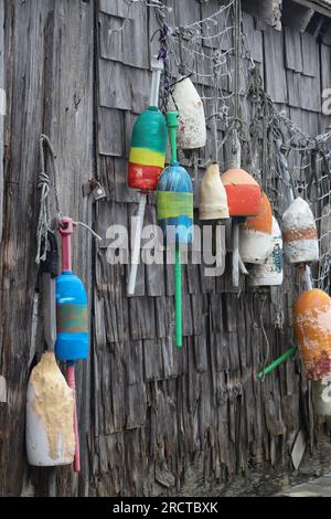 bouées colorées et filet accrochés sur un mur de bois patiné d'une cabane Banque D'Images