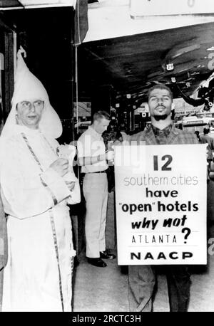 Atlanta, Géorgie : 3 juillet 1962 Un délégué à la convention NAACP pivote devant un hôtel du centre-ville pour protester contre sa politique de ségrégation tandis qu'un membre du Ku Klux Klan distribue de la littérature soutenant leur position. Banque D'Images