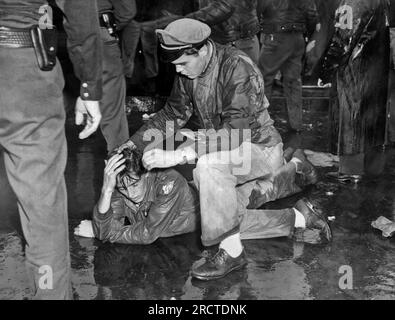 Los Angeles, Californie : 1 octobre 1946. Un manifestant blessé aux studios MGM repose sur le trottoir alors qu'un camarade tente de l'aider après la bataille avec la police et les shérifs adjoints. De nombreux paradisiaques sont des anciens combattants qui ont été mis en lock-out pendant la grève. Banque D'Images