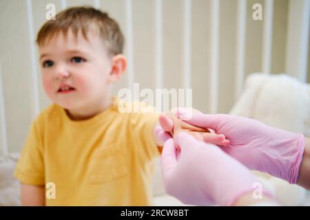 Le médecin fait de la gymnastique et des massages des mains à un bébé tout-petit. Infirmière en uniforme faisant des exercices orthopédiques de doigt de main à l'enfant. Enfant âgé d'environ deux ans Banque D'Images