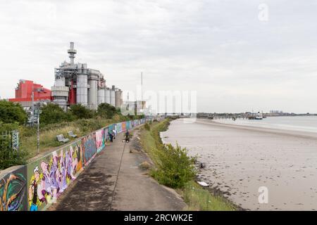 Deux artistes graffiti au travail sur la digue de la Tamise, Thurrock, près de Grays, Essex. Usine Procter et Gamble à distance. Banque D'Images