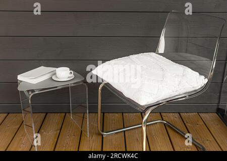 Meubles en acrylique moderne transparent transparent dans la maison. Chaise avec oreiller, table d'appoint avec tasse à thé et livre. Concept de matériau de meuble alternatif. Banque D'Images