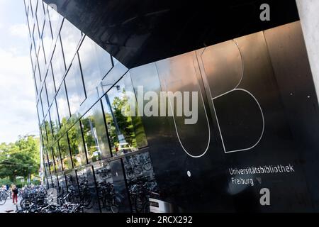 Freiburg im Breisgau, Allemagne. 13 juillet 2023. Les vélos sont garés devant le bâtiment de la bibliothèque universitaire dans le centre-ville de Fribourg tandis que le lettrage «UB Universitätsbibliothek Freiburg» peut être lu sur la façade. Crédit : Philipp von Ditfurth/dpa/Alamy Live News Banque D'Images