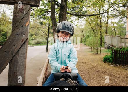 fille âgée de 4 ans souriant tout en montant un cheval dans la forêt Banque D'Images