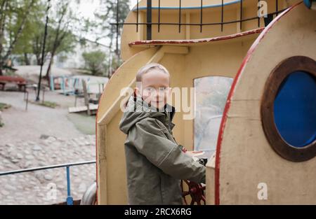 jeune garçon souriant tout en conduisant un bateau jouet Banque D'Images