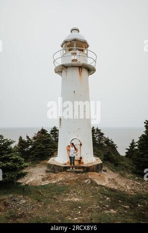 Femme debout devant un vieux phare à Terre-Neuve, Canada. Banque D'Images