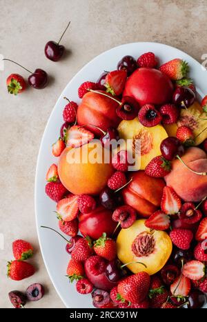 Gros plan d'un plateau de fruits mélangés : baies, pêches, cerises. Banque D'Images