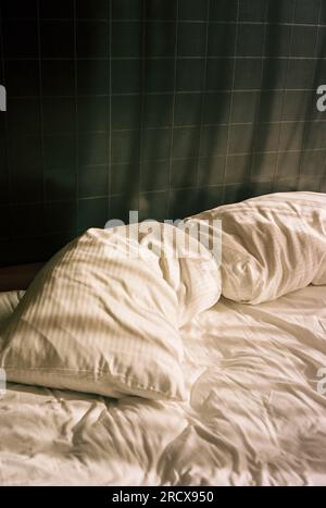 Une scène tranquille d'un lit de sommeil vide avec des draps blancs froissés Banque D'Images