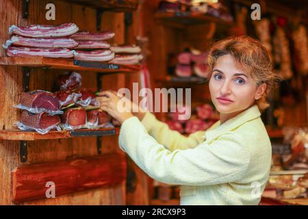 Une jeune femme choisit de la viande sur un marché Banque D'Images