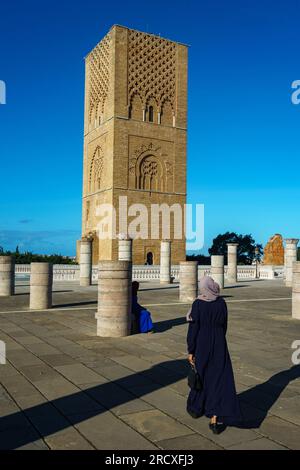 Maroc. Rabat. Une femme se promène devant la magnifique Tour Hassan et ses colonnes de pierre sur l’esplanade de Yacoub al-Mansour. La tour est incomplète Banque D'Images