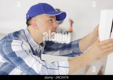 un technicien travaillant sur le thermostat Banque D'Images