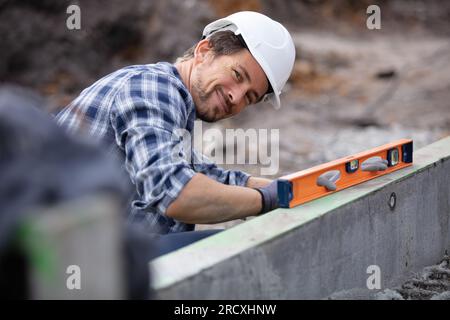 bricklayer mettant en bas une autre rangée de briques dans l'emplacement Banque D'Images