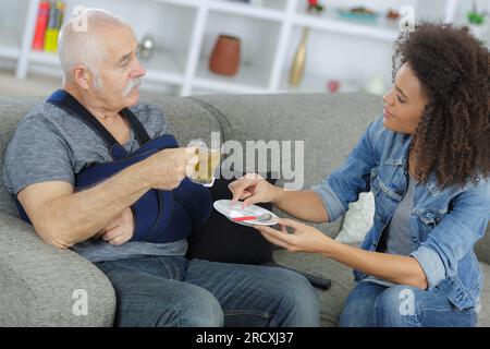 femme servant le thé au vieil homme en convalescence Banque D'Images