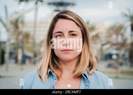 Portrait individuel en gros plan d'une jeune femme adulte sérieuse debout à l'extérieur avec une expression pensive. Photographie en tête d'une femme assez confiante regardant bien la caméra. Vraie dame formelle regardant devant. Photo de haute qualité Banque D'Images