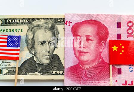 Un billet de 20 USD et un billet de banque chinois de 100 yuans avec les drapeaux nationaux américains et chinois isolés en blanc. Finance internationale, concurrence commerciale co Banque D'Images