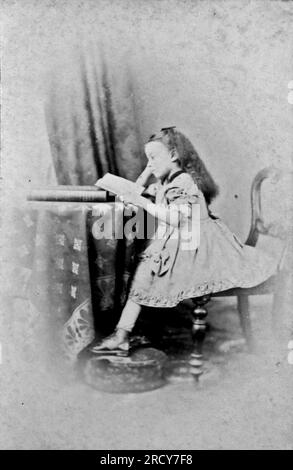 Portrait d'une fille assise et lisant un livre. Photographie originale de Monsr. Louis de 333, Euston Road, Londres et Boulogne. D'une collection de photographies victoriennes carte de visite, datées des années 1890 Carte de visite est un terme français connu en anglais sous le nom de « Visiting card ». Ils avaient généralement un tirage photographique albumen d'environ 54x89mm monté sur une carte légèrement plus grande. Dans certains cas, les ravages du temps ont fait leurs ravages. Banque D'Images