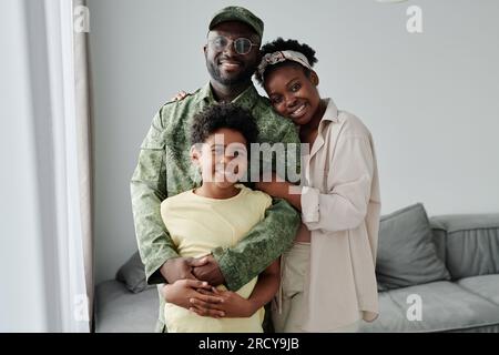 Portrait de la famille afro-américaine heureuse de trois souriant à la caméra, ils rencontrent leur père de la guerre Banque D'Images