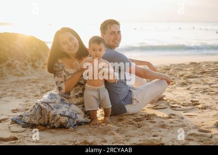 Une famille heureuse jouant à la plage pendant l'heure d'or à Bali, Indonésie Banque D'Images