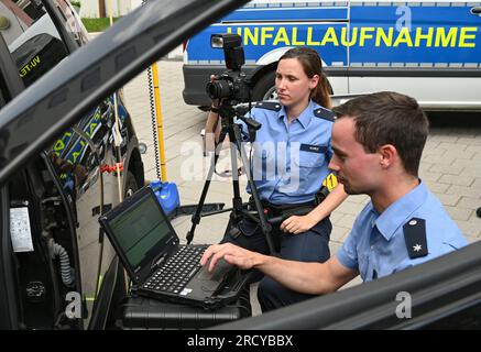 Mayence, Allemagne. 17 juillet 2023. Julia Kurz (arrière), commissaire de police, et Dominik Knopp, commissaire de police, de l'équipe d'enregistrement des accidents de la circulation montrent dans la cour du ministère de l'intérieur comment lire l'interface OBD d'une voiture et enregistrer les dommages à l'aide d'un appareil photo numérique. La police de Rhénanie-Palatinat prévoit de déployer des équipes pour enregistrer les accidents de la circulation dans l'État en utilisant une technologie numérique spéciale. En plus de la formation professionnelle spéciale, les équipes disposeront d'un équipement technique spécial. Crédit : Arne Dedert/dpa/Alamy Live News Banque D'Images
