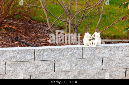 2 petits personnages de grenouilles blanches assis sur un mur. Photo de haute qualité Banque D'Images