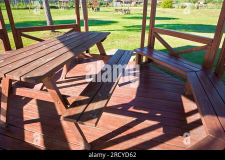 Table de pique-nique en bois dans un belvédère en bois sur un pré vert dans un parc public. Banque D'Images