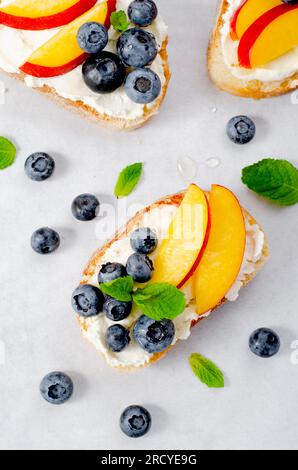 Pain grillé maison avec myrtille, pêche et fromage à la crème, délicieux snack ou petit déjeuner sur fond lumineux Banque D'Images