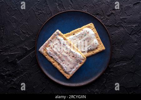 Placez les tartes sur une assiette. Poptart grille-pain pâtisserie avec glaçage sur un fond d'ardoise noire, plan de pose plat au-dessus de la tête Banque D'Images