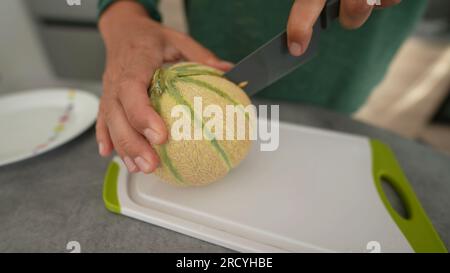 Main coupant melong fruit gros plan mains tenant le couteau tranchant le dessert sain Banque D'Images