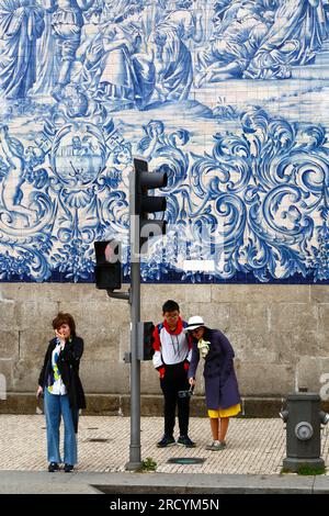 Un jeune couple asiatique prend un selfie devant les azulejos / carreaux de céramique sur le mur latéral de l'église d'Igreja do Carmo, Porto / Porto, Portugal Banque D'Images