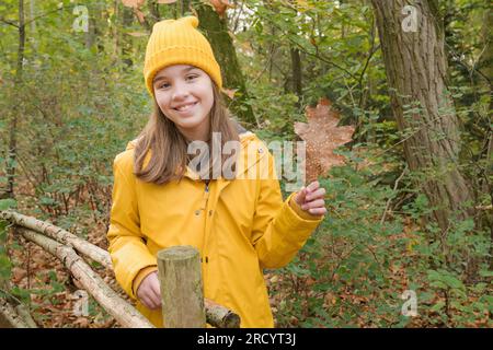 Une adolescente marche dans le parc d'automne. Portrait depuis l'avant. Le modèle regarde dans la caméra. vêtements jaune vif Banque D'Images