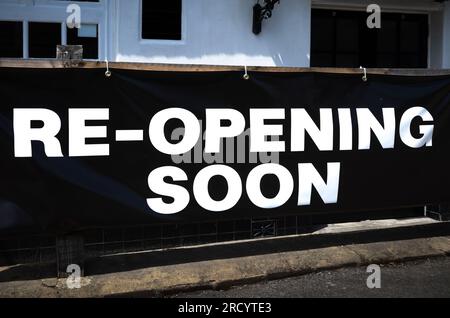 Un grand panneau imprimé sur une feuille de plastique indiquant « Re-opening Soon » apposé à l'avant d'un pub à Billingshurst, West Sussex, Royaume-Uni. Banque D'Images