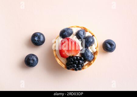 Tartelettes savoureuses avec de la crème fouettée et des baies sur fond beige Banque D'Images