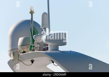 Gros plan vue partielle du bateau à moteur de loisirs blanc de haute qualité avec drapeau de klaxon de projecteur de radar monté et antennes comme concept pour l'orientation et la communication Banque D'Images