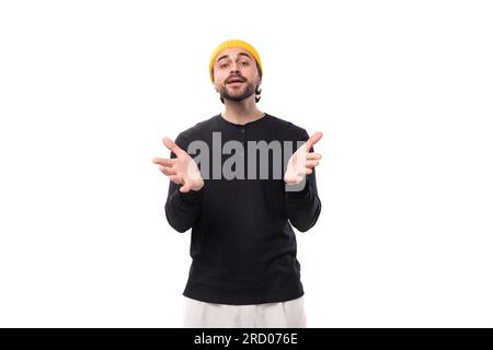 jeune homme de brunette caucasien bien entretenu avec une barbe dans un style informel montre ses mains sur le côté Banque D'Images