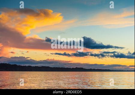 Coucher de soleil éclairant les nuages sur la rivière Madre de Dios au Pérou. Banque D'Images