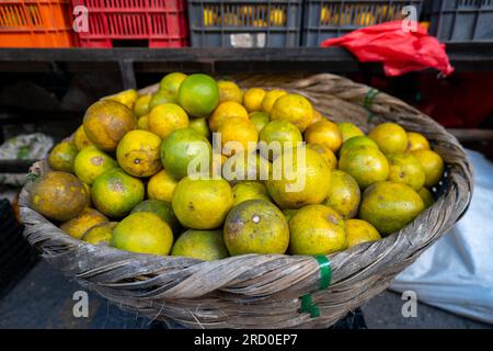 Oranges dans un panier en bois dans le marché coloré 'Mercado Mayoreo' près du stade national de Tegucigalpa avec des produits et des étals Banque D'Images