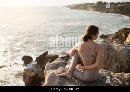Jeune athlète européenne mince en vêtements de sport pratique le yoga en plein air, aime l'entraînement Banque D'Images