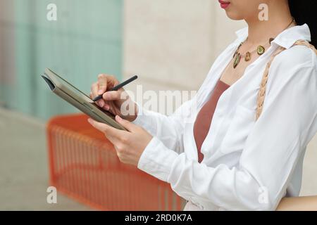 Image recadrée d'une femme d'affaires remplissant un document sur une tablette Banque D'Images