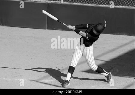 Un joueur de softball de baseball est balancer la batte frappant la balle noir et blanc Banque D'Images