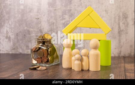 Figurines en bois d'une famille et une carte de crédit près d'une maison blanche. Le concept d'un prêt au logement pour une jeune famille nombreuse Banque D'Images