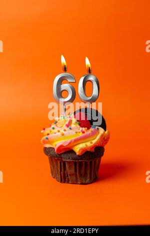 gâteau d'anniversaire avec le numéro 60 - cupcake sur fond orange avec bougies d'anniversaire Banque D'Images