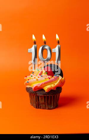 gâteau d'anniversaire avec le numéro 101 - cupcake sur fond orange avec bougies d'anniversaire Banque D'Images