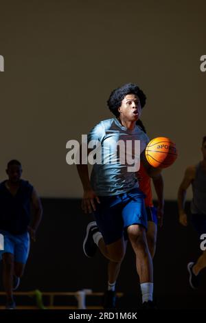 Divers joueurs de basket-ball masculins portant des vêtements de sport bleus et jouant au basket-ball à la salle de gym Banque D'Images