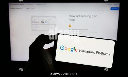 Personne tenant le téléphone portable avec le logo du produit marketing Google Marketing Platform sur l'écran en face de la page Web d'entreprise. Concentrez-vous sur l'affichage du téléphone. Banque D'Images